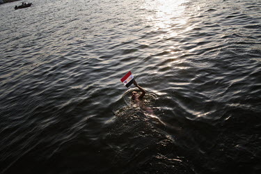 A young man, holding an Egyptian flag, swims in the Nile River. 25 January 2011 saw the beginning of a nationwide 18 day protest movement that eventually ended the 30-year rule of Hosni Mubarak and hi...