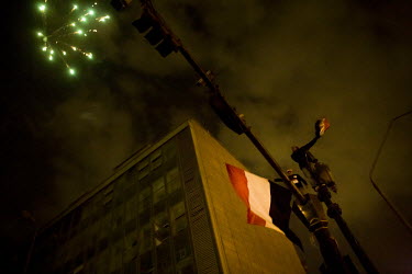 A firework explodes above two flag waving men, on top of a lamp post,  as hundreds of thousands of people, from all over Egypt, descend into Tahrir Square to join in the celebration at the news that H...