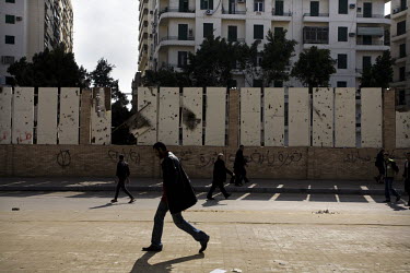 People walk past a wall displaying scars of violence from the previous weeks of protest on the 12 February 2011, the morning after the resignation of Hosni Murbarak. 25 January 2011 saw the beginning...