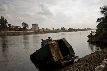 A destroyed amoured police van that has been driven into the river Nile. On the opposite bank is a prison that was overrun by protestors and rioting prisoners. 25 January 2011 saw the beginning of a n...