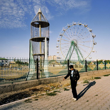A young Karakalpak walks past the amusement park in central Nukus. With only a handful of the rides working, it's still one of the largest attractions in the area, with many wedding celebrations takin...