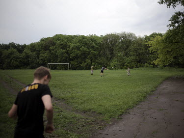Young boys throw a rugby ball about in a park.