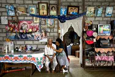 Pedro and Catalina Franco sit, surrounded by family photographs and ornaments, in their house in the hacienda La Mariana.