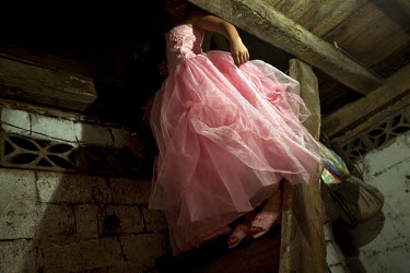 Yessenia Aguayos walks down a staircase in her grandparent's house during her quinceatera (fifteenth birthday) celebrations.