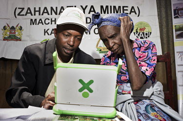 Farmers examine information on plant diseases using an OLPC-Green laptop at a Plant Health Clinic on market day in a village near Machakos. Farmers visiting the market can come to see a plant patholog...