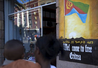 a poster on a wall outside a shoe shop featuring an Eritrean flag and the slogan ^Welcome to free Eritrea^.