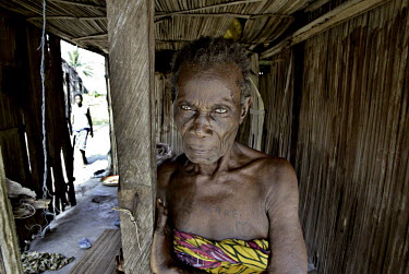 A Ijaw woman with tattoos stands in her house.