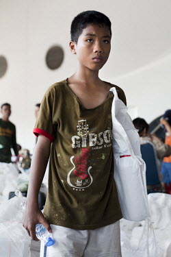 A boy made homeless by flooding carries an assistance package in an evacuation centre established at Thammasat University. Large parts of central and northeastern Thailand have been severely affected...