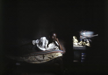 Venant Shyirambezre, who caught the HIV virus from his wife, sits at home.