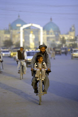 A father and his son ride a bike a long a road in Mazra-i-Sharif, Afghanistan.