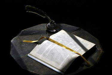 A book and a quill and ink on a table at the Jane Austen House Museum, Chawton, near Alton, Hampshire, UK.