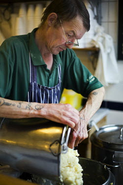 A chef empties mashed potato into buckets at the counter of F Cooke's Pie and Mash shop in Hoxton, London.