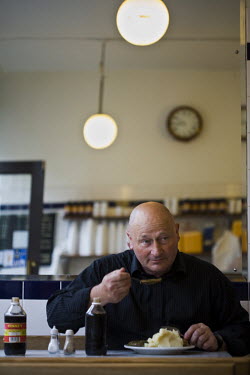 A customer eats a plate of eels, pie and mash at F Cooke's Pie and Mash shop in Hoxton, London.