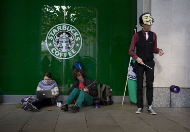 Occupy London protestors outside a Starbucks cafe near St Paul's Cathedral in the City of London using a laptop, playing a guitar and practicing tricks. The protest is part of a worldwide movement aga...