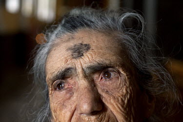 An elderly woman with a cross of ashes smeared on her forehead for Ash Wednesday, the end of Carnival and the beginning of Lent.