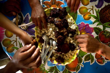 A family eats fritada and mote (fried pork and corn) with their neighbours during Carnival when people dance house to house, sharing food.