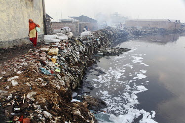 A woman walks along the Buriganga River whose banks are made of piles of rubbish. Everyday 1.5 million cubic metres of waste water from 7,000 industrial units in surrounding areas and another 0.5 mill...