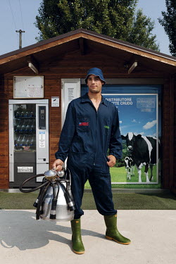 A dairy farmer stands in front of the fresh milk dispenser that he has had installed.