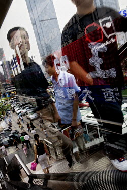 People using an escalator are reflected in the window of a building in central Shanghai.