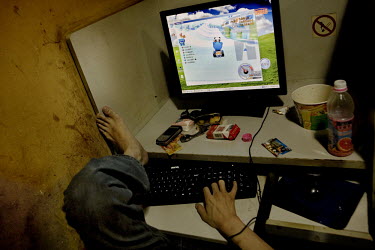 A man uses a computer in an internet cafe.
