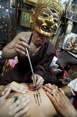 Tattoo master (khru Sak) Ajarn Thoy Dabos makes a Sak Yan or Sacred Tattoo on a disciple (luuk sit). Dabos is a reussi, a mendicant whose tattoos are possessed by the spirit of Pho Khae, an old man fr...