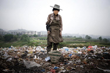 71 year old Fang Xin Nan scavenging on a rubbish dump outside the village of Luoqi.
