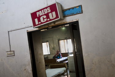 A woman and child sit on a bed in the Paediatric ICU ward being treated for acute respiratory illness (ARI). Acute respiratory illnesses and skin diseases are common consequences of malnutrition, due...