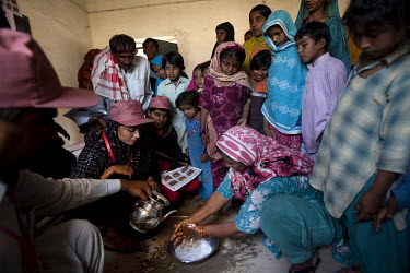 Women and children watch and listen as WHO-sponsored NGO workers give a lesson in hand-washing and basic health and hygiene in a rural village outside Naushero Feroz.