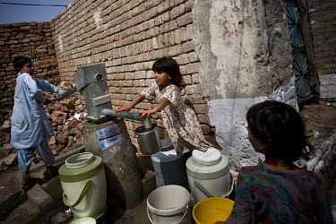 Children collect water at a newly installed pump that provides clean drinking water for the village of Kheshgi Bala.