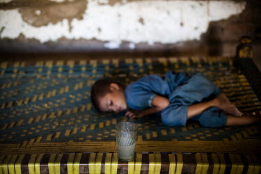 A boy sleeps on a charpoy (daybed) in his family home. He was discharged from the nutrition stabilisation centre in Jamsharoo, after being admitted with severe malnutrition brought on by TB and pneumo...