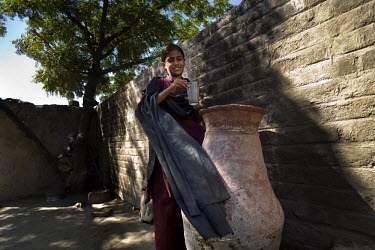 A young woman collects a glass of untreated water from a vessel outside her home.  Unclean water is one of the contributing factors that annually produce very high levels of malnutrition amongst child...