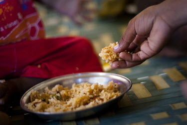 A child eats a dish of rice at their family home. Poor diet and food hygiene is one of the contributing factors that annually produce very high levels of malnutrition amongst children.
