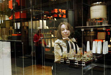 A woman looks out of the window of a perfume shop in central London.