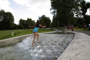A young girl runs up a water feature in Hyde Park, London.