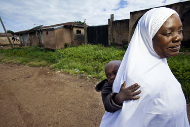 A woman carries her baby through the Dutse Uku district of the city, mostly inhabited by Muslims. Continued violence between Christians and Muslims has torn the city of Jos apart.