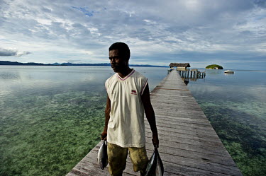 A fisherman carries his catch of Horse Mackeral along a jetty on the Raja Ampat Islands.