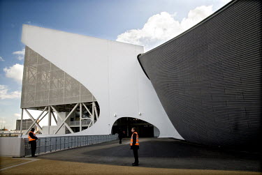 Security guards stand in front of the aquatics centre (diving and swimming) with temporary wings by architect Zaha Hadid in the Olympic Park in East London. With the temporary wings the building can a...