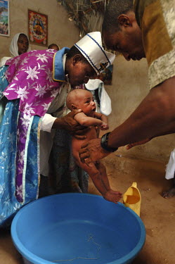 A priest baptises a child in St Mary's church in the village of Fithi ('Justice').