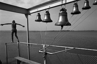 A boy jumps of a barge which has a set of bells and acts as a floating church on the Volga - Don Canal near Volgograd.