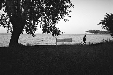 A boy walks past a bench on the banks of the Volga River in the village of Chkalovsk.