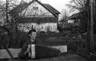 A man plays his accordion on a bench in the village of Ivtsino.