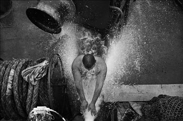 A crew member of the cargo ship 'Anatoly Torchinov takes a shower on the deck of the ship.