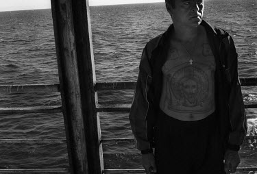 A man with a tattoo of Jesus Christ on his chest and stomach stands on board a ferry travelling from the mainland to Sakhalin island.