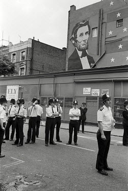 Policemen on the corner of Westbourne Park Road and Portobello Road during the Notting Hill Carnival. They are standing beneath a mural of Abraham Lincoln.