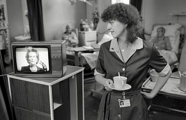 A domestic worker on a ward in St Charles Hospital, Notting Hill, London, watches a speech by Prime Minister Margaret Thatcher. The company she was employed by, Mediclean, had recently been awarded th...