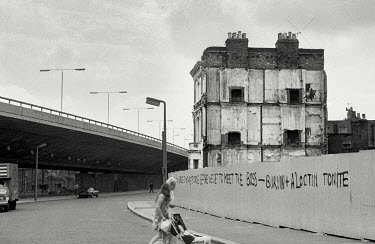 A house, about to be demolished, on Acklam Road in Notting Hill, West London. It is next to the Westway flyover (A40). Graffiti on the fence that cordens the house off from the road reads: 'HOW MANY B...