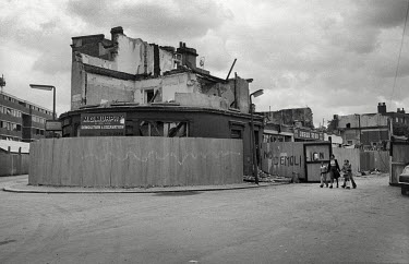 A woman and two children walk past partially demolished shops and housing on Clarendon Road in Notting Hill, West London.
