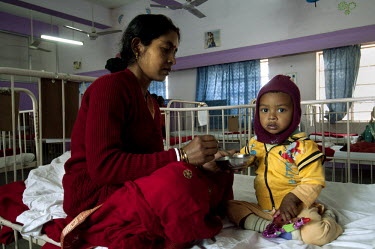 A mother feeds her sick child on the children's ward of the Tata Main Hospital.