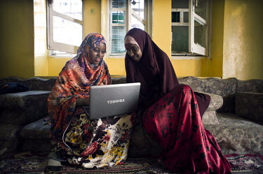 Two students from Mogadishu University use a laptop as they study at home.