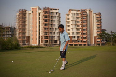 12 year old Okkar Myo practices putting at an exclusive golf club in front of a luxury apartment development in Yangon. Despite the political reforms taking place in Myanmar, there is massive poverty...